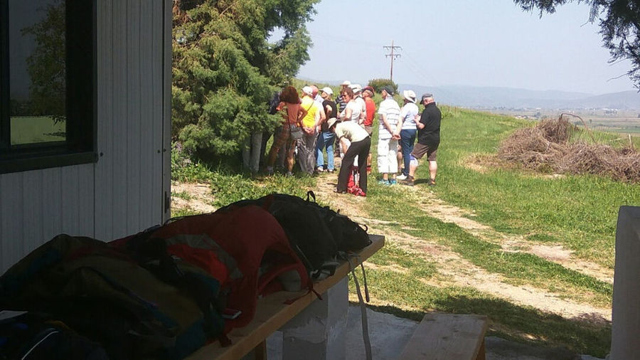 bags on the wood table and tourists wait in the shade of the tree at Bio Goupios